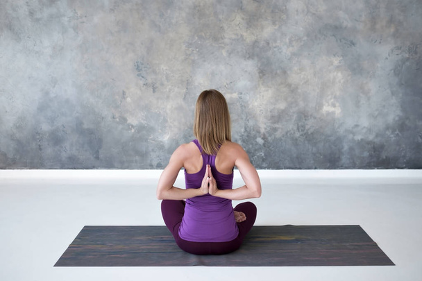 Mladá žena trénuje jóga, sedí s Namaste za zády a pracuje - Fotografie, Obrázek