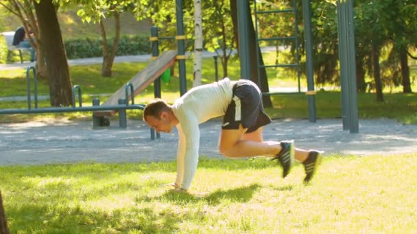 bodybuilder homme athlétique fait des fentes, en prenant l'accent couché. sur un champ vert au milieu d'un parc
 - Séquence, vidéo