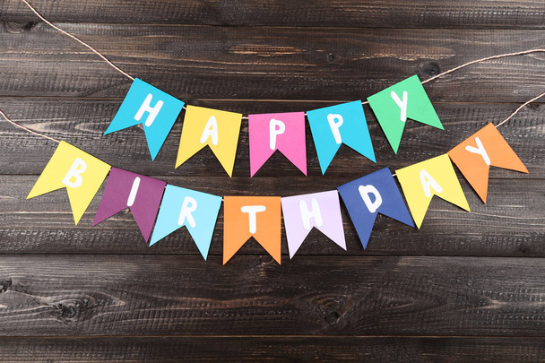 Paper flags with text Happy Birthday on wooden background - Valokuva, kuva