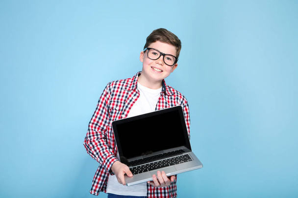 Young boy holding a laptop on blue background - Foto, imagen
