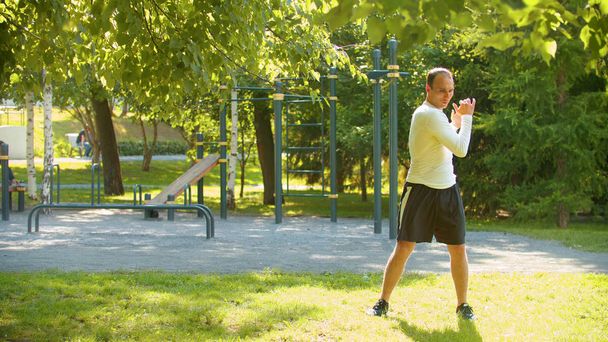 Um homem atlético aquecendo com exercícios básicos no parque
 - Foto, Imagem