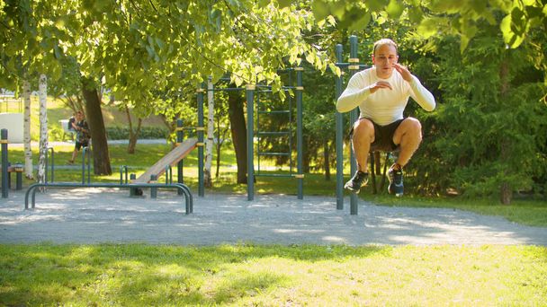 Um homem atlético se aquecendo no parque - pulando
 - Foto, Imagem