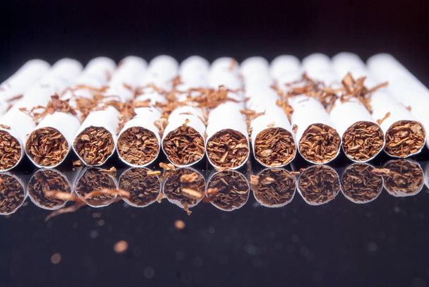 Empilhamento de cigarros no fundo preto
 - Foto, Imagem