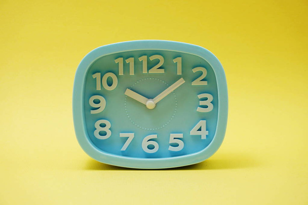 light blue alarm clock with space copy on yellow background - Foto, Bild