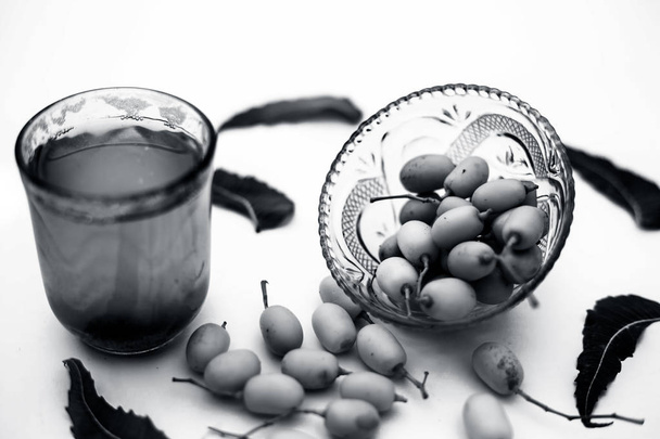 Detox or detoxifying drink of neem fruit in a glass isolated on white along with some neem fruit or nimbodi or nimbudi in a glass bowl.Horizontal shot. - Fotó, kép