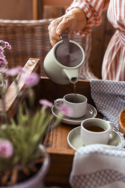 A woman pours tea into a mug of tea. Cozy atmosphere and homemad - Valokuva, kuva
