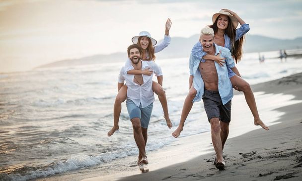 Baráti társaság fut a strandon, és élvezi a nyári vakáció - Fotó, kép