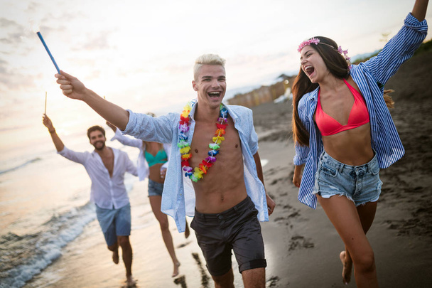 Group of friends running on beach and enjoying summer holiday - Photo, image