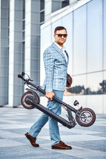 Homem elegante está segurando eletro scooter
 - Foto, Imagem