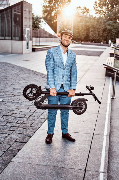 Elegante hombre está sosteniendo electro scooter
 - Foto, Imagen