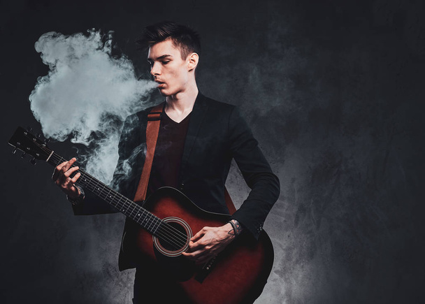 Ελκυστικός τύπος παίζει ακουστική κιθάρα και το κάπνισμα - Φωτογραφία, εικόνα