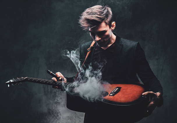 Attraente ragazzo sta giocando la chitarra acustica e il fumo
 - Foto, immagini