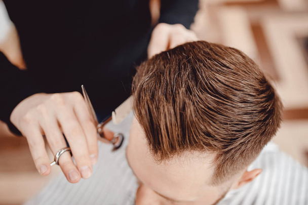 Close-up Master Barber doet kapsel en styling met droger haar naar Guy. Concept Barbershop - Foto, afbeelding
