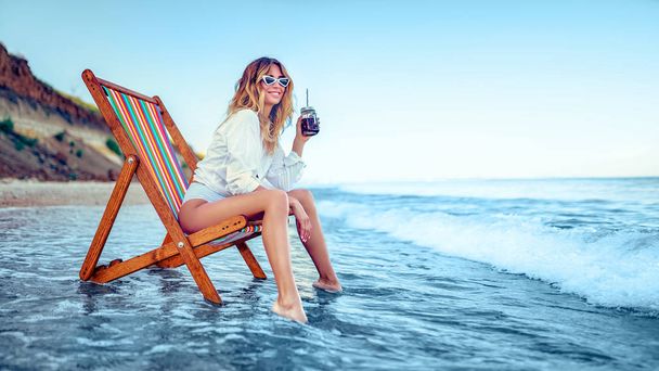 Pretty woman relaxing on a lounger beach and drinks soda water. summer vacation concept - 写真・画像