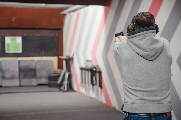 Homem dirige pistola de arma de fogo na faixa de tiro alvo ou alcance de tiro
 - Foto, Imagem