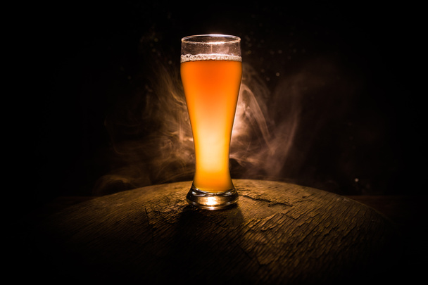 Concepto creativo. Vasos de cerveza sobre mesa de madera en fondo nebuloso tonificado oscuro
. - Foto, imagen