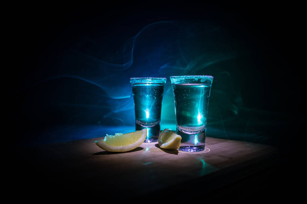 Концепция напитков. Вкусный алкоголь коктейль текила с лаймом и солью на ярком темном фоне или очки с текилой в баре
 - Фото, изображение