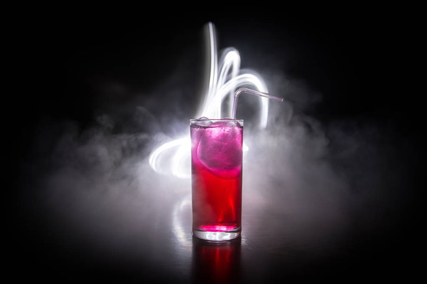 Склянка коктейлю розбризкується на темному тонованому димчастому фоні або барвистому коктейлі в склі. Вечірній клуб розваг. Змішане світло
. - Фото, зображення