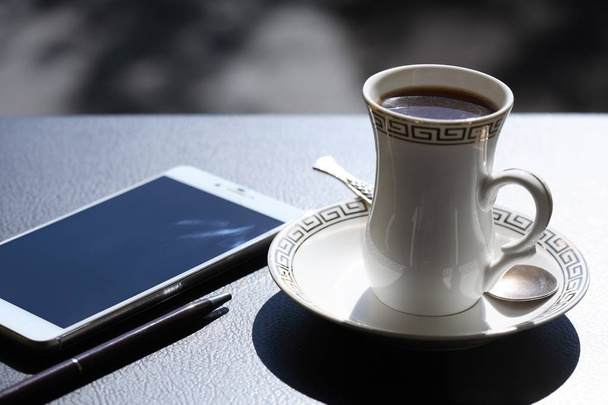 Φλιτζάνι τσάι κοντά στο τηλέφωνο - Φωτογραφία, εικόνα