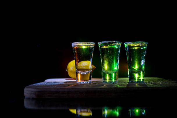 Концепція клубного напою. Смачний алкоголь п'ють коктейль текіла з лаймом і сіллю на яскравому темному фоні або келихах з текілою в барі
 - Фото, зображення
