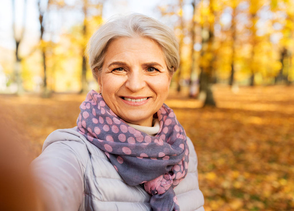 Seniorin macht Selfie im Herbstpark - Foto, Bild