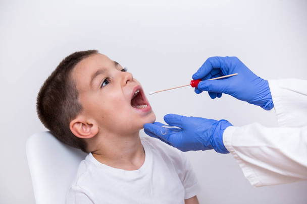 Lekarz widok zbliżenie ręce w rękawiczkach za pomocą wacika do testowania młody chłopak zakażeń bakteryjnych - Zdjęcie, obraz