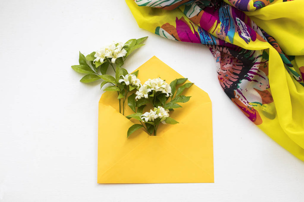 білі квіти жасмину місцева флора Азії в жовтому конверті з шарфом жінки способу життя на фоні білого
  - Фото, зображення