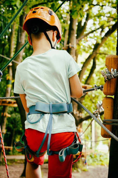 Мальчик взбирается по веревочному парку
 - Фото, изображение