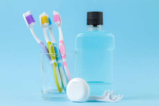 Στοματική υγιεινή. Οδοντόβουρτσα, οδοντικό νήμα και ξεπλύνετε για το στόμα και τα δόντια σε ένα απαλό μπλε φόντο - Φωτογραφία, εικόνα