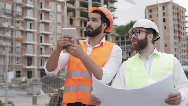 The builder and architect on construction site photographing with the tablet work and checking with construction plan. - Imágenes, Vídeo