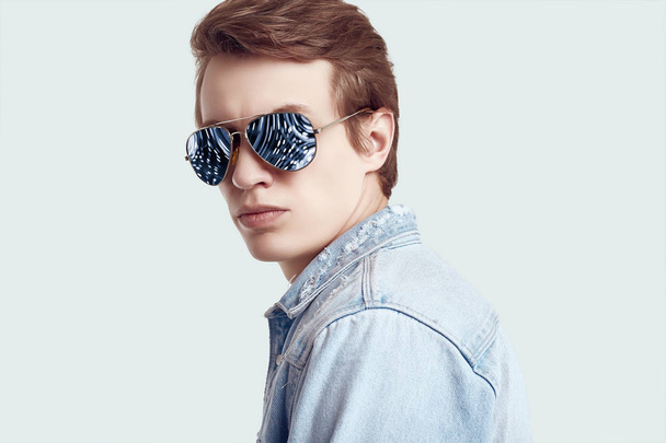 Handsome hipster man in fashion sunglasses wearing jeans jacket - 写真・画像