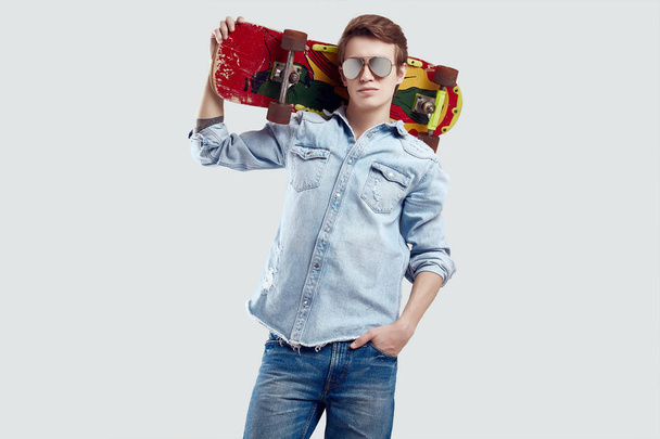 Hipster muž s brýlemi a džíny a kabátem s skateboard - Fotografie, Obrázek