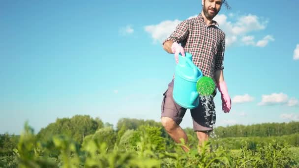 Young handsome hipster man watering the garden with a country watering can. - Footage, Video