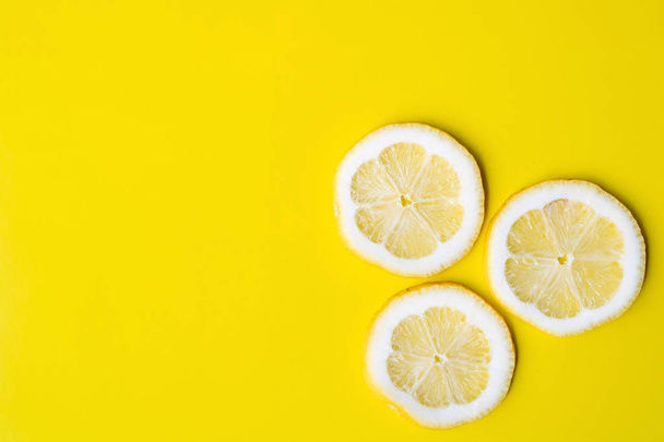 Три ломтика лимона на ярко-желтом фоне
 - Фото, изображение