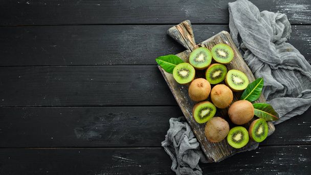 Fresh kiwi and green leaves on the table. Rustic style. Fruits. Top view. Free space for text. - 写真・画像