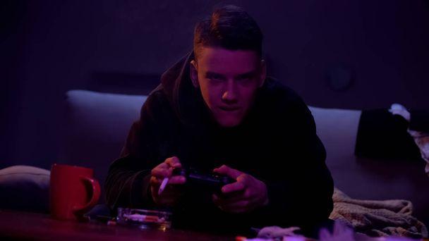 Aggressive teenage boy smoking and playing video game, nicotine addiction - Foto, immagini