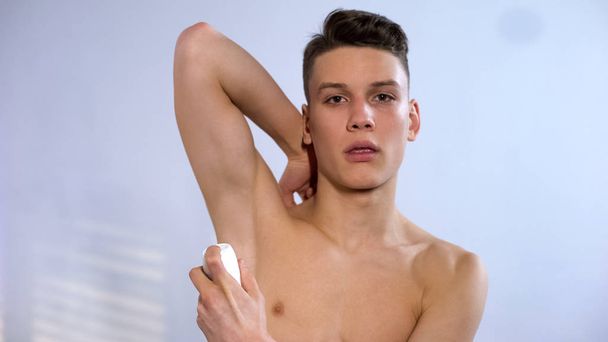 Teenage boy applying roll antiperspirant morning hygienic procedures puberty age - Zdjęcie, obraz