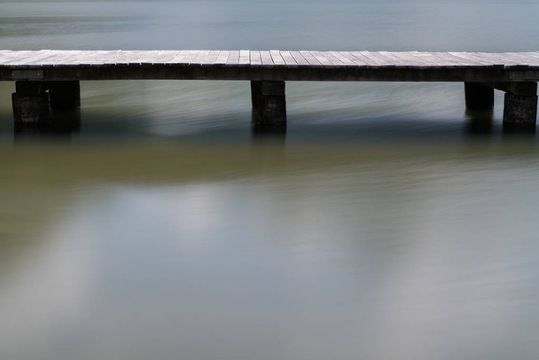 long wooden boardwalk on a calm and placid mountain lake abstrac - Photo, Image