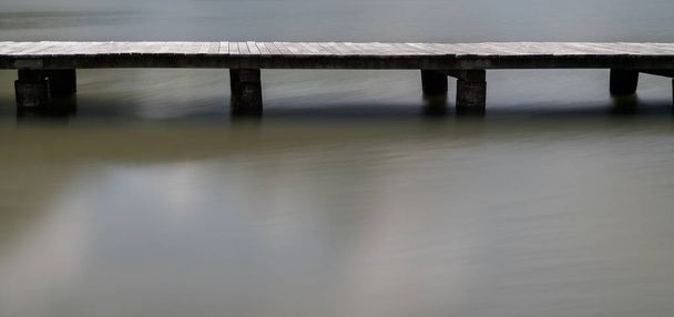 longo calçadão de madeira em um lago de montanha calmo e plácido abstrac
 - Foto, Imagem
