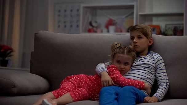 Brother embracing girl, watching horror movie, protecting sister from monsters - Zdjęcie, obraz