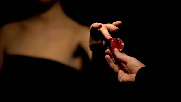 Man proposing woman poker chip, inviting for game, isolated on black background - Φωτογραφία, εικόνα