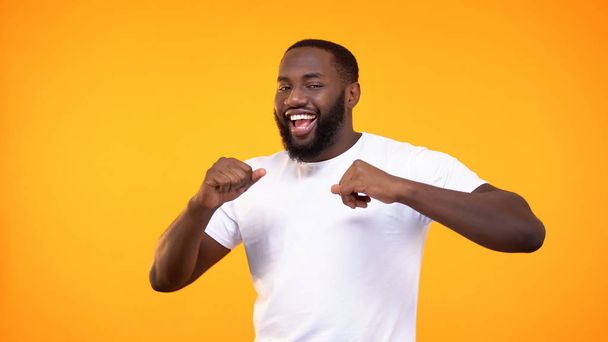 Joyful black male dancing on bright background, achievement happiness, fun - Фото, изображение