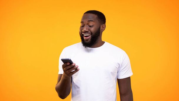 Amazed african man browsing smartphone internet, online application, cash back - 写真・画像