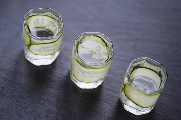 Vodka in shot glasses with cucomber on rustic wood backgroun - Fotoğraf, Görsel