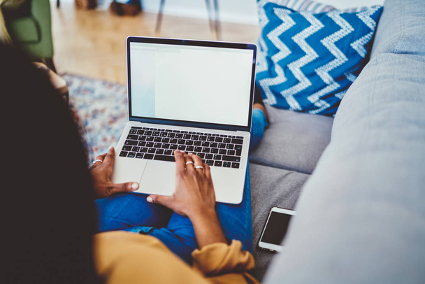 Обрізане зображення темношкірої жінки, що друкує на ноутбуці з маком uo екран витрачає час на домашній інтер'єр, фрілансерка, що працює дистанційно лежить на дивані з сучасною нетбуком, підключеною до wif
 - Фото, зображення
