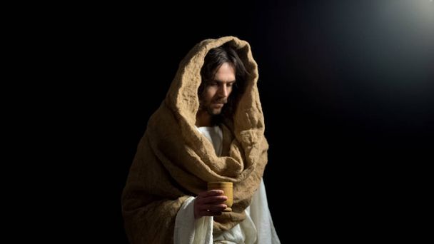Upset man in robe holding wooden mug, christian help for hungry beggar, mercy - Valokuva, kuva