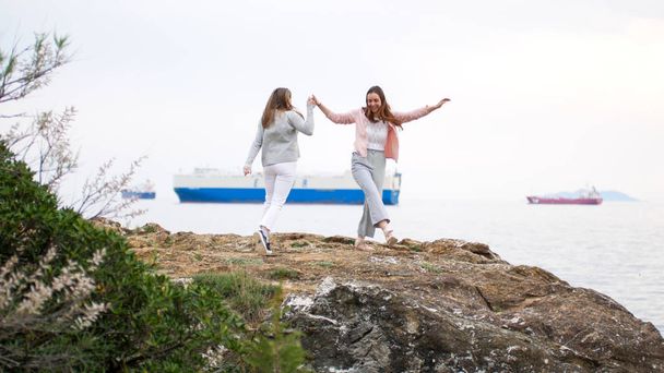 Dos jóvenes bailando en la costa rocosa
 - Foto, imagen