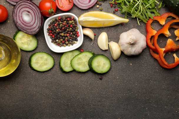 Ingredienti per la cottura dell'insalata. Varie verdure e spezie carote, pomodori, cipolle, cetrioli, peperoni e rucola su sfondo scuro. vista dall'alto
. - Foto, immagini