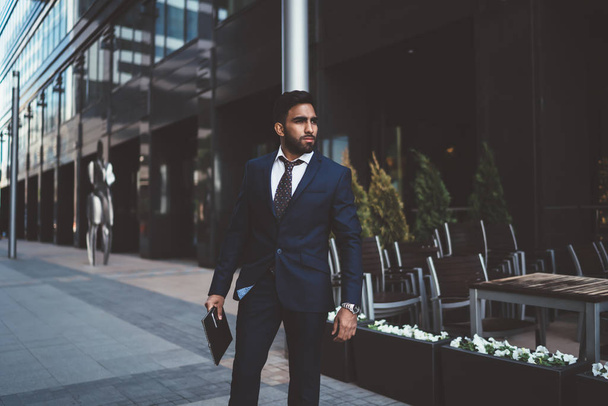 Confident business man dressed in stylish elegant suit standing on publicity area with folder in hand and waiting colleague, pensive mature male director looking away in financial district - Φωτογραφία, εικόνα