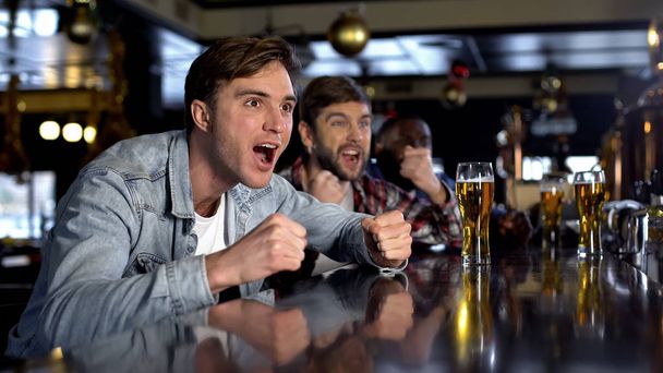 Male supporters watching sport program in bar celebrating victory, true men rest - Foto, Bild